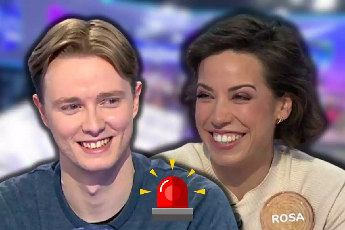 Manu y Rosa sonrientes en un programa de televisión con un icono de alarma roja en el centro.