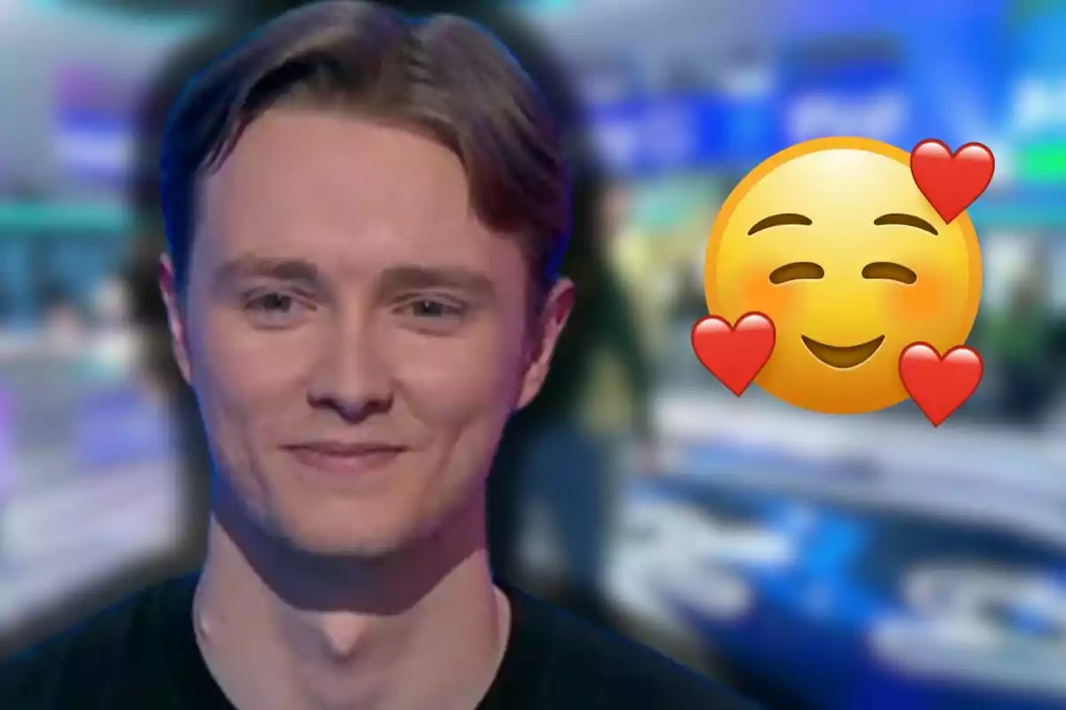 Manu sonriente con fondo desenfocado y un emoji de carita feliz con corazones a un lado