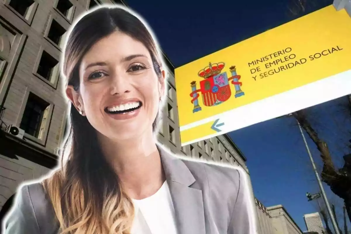 Una mujer sonriente frente a un edificio con un cartel del Ministerio de Empleo y Seguridad Social de España.