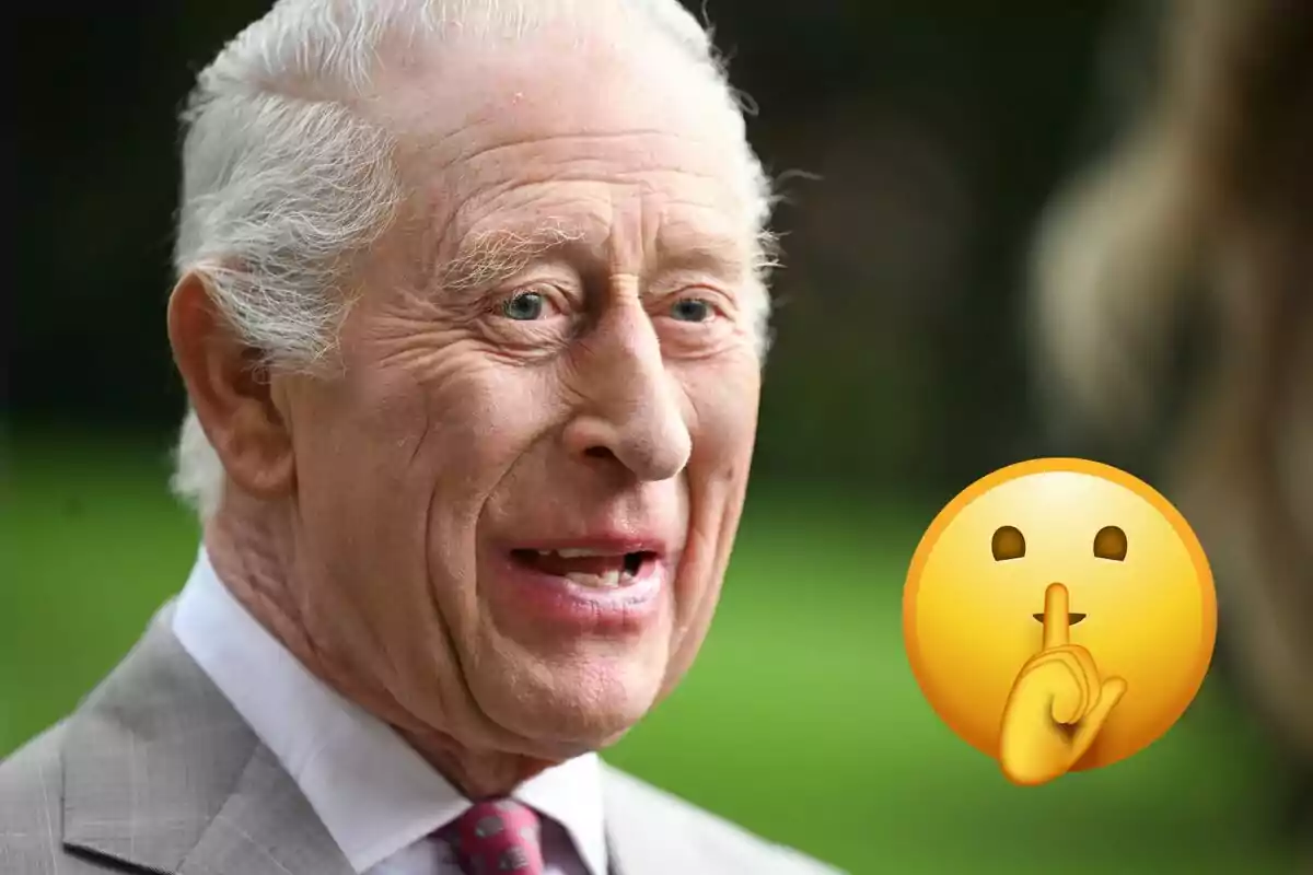 Carlos III con traje sonríe mientras un emoji de silencio aparece a su lado.