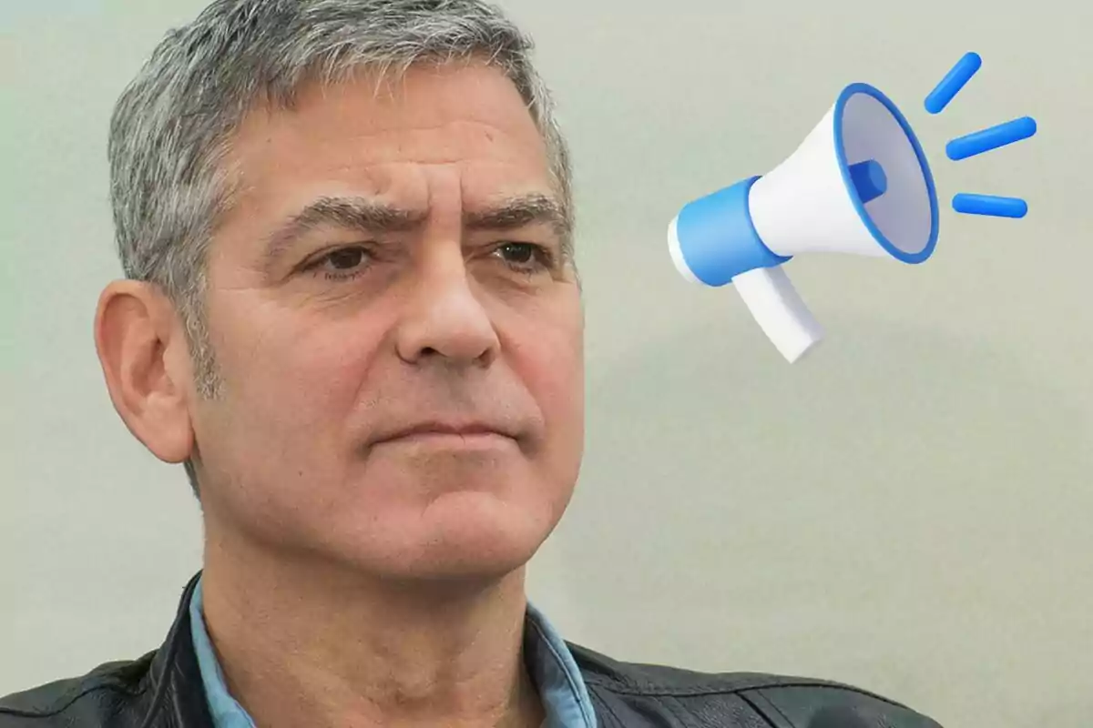 George Clooney con una chaqueta oscura y una camiseta azul, junto a un megáfono azul y blanco.