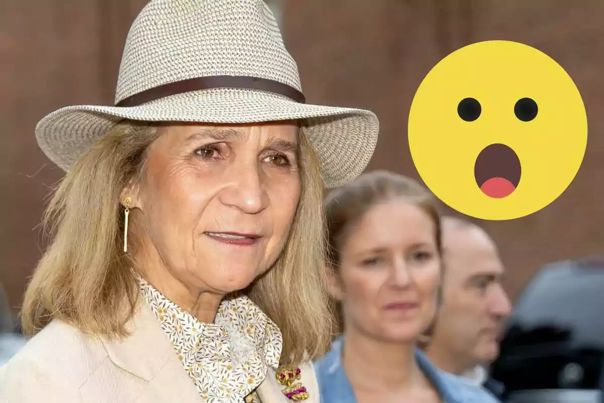 La infanta Elena con sombrero de paja y expresión seria está en primer plano mientras un emoji sorprendido flota a su lado.