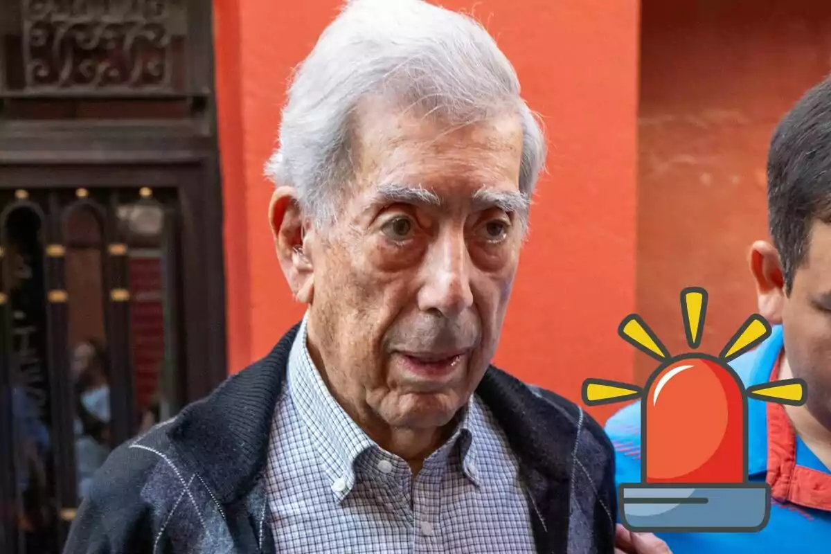 Mario Vargas Llosa con cabello canoso y expresión seria, acompañado por otra persona, con un ícono de sirena de emergencia superpuesto en la imagen.