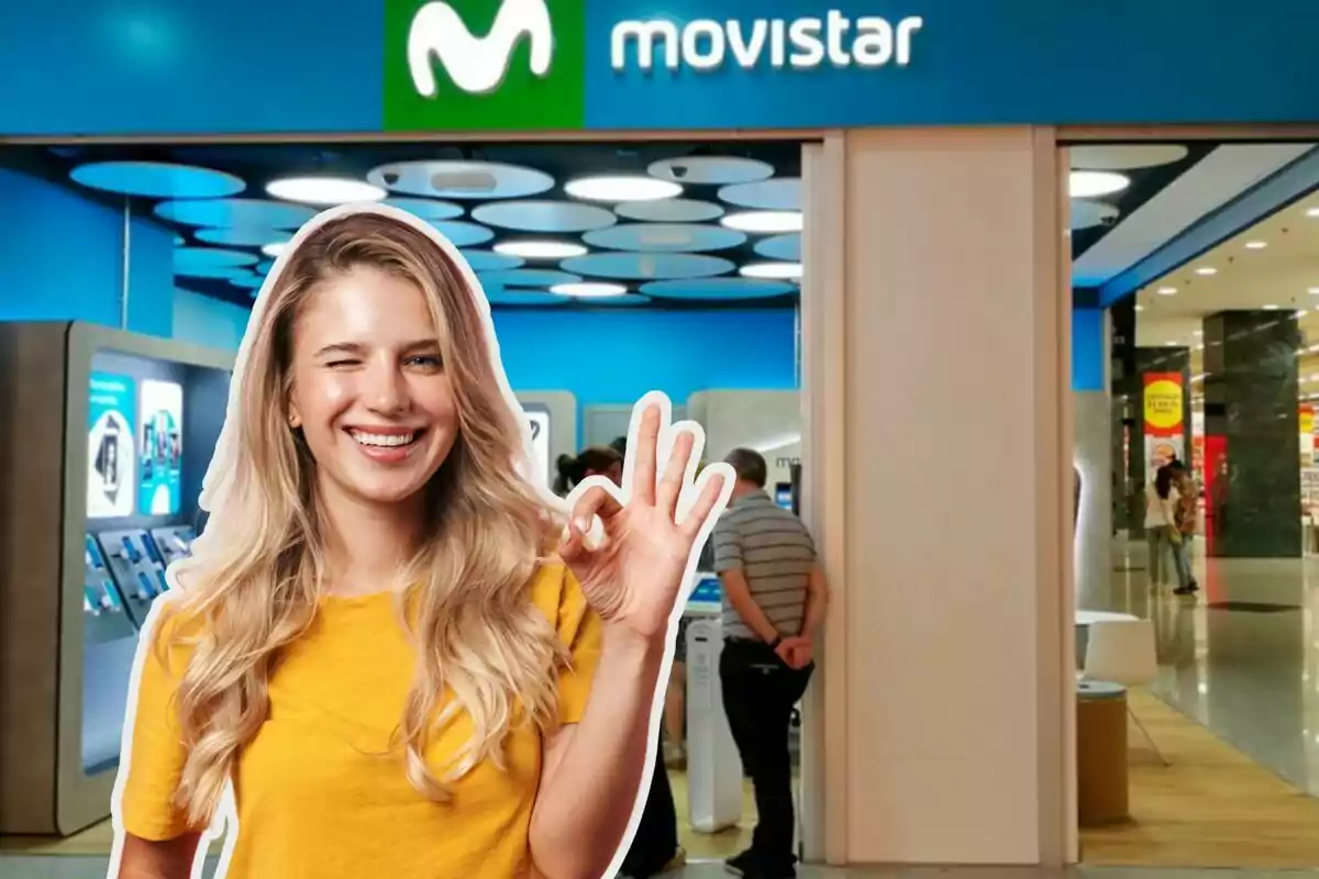 Una mujer sonriente con camiseta amarilla hace un gesto de "ok" frente a una tienda de Movistar.