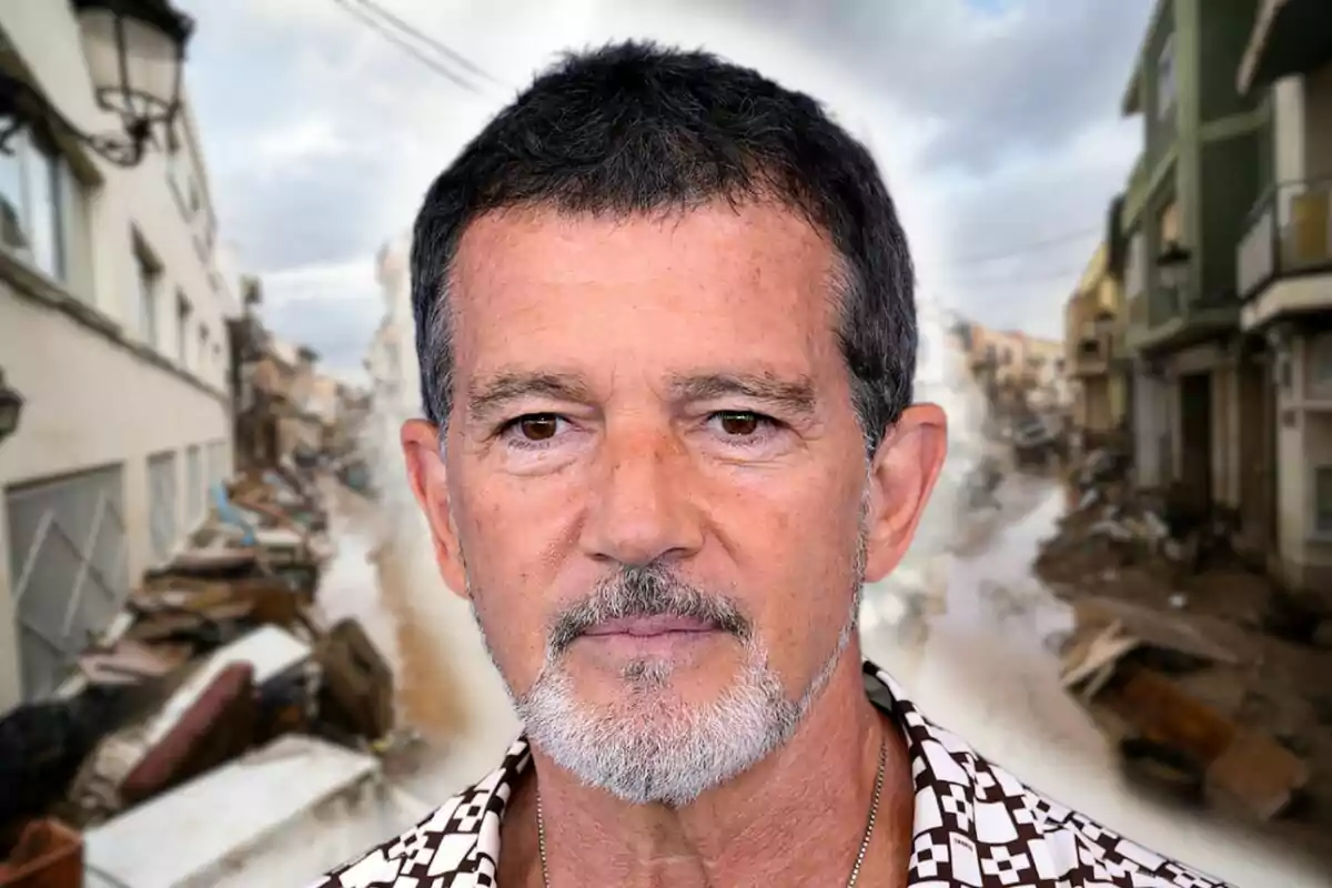 Antonio Banderas de cabello oscuro y barba canosa está frente a un fondo de una calle con escombros y edificios dañados.