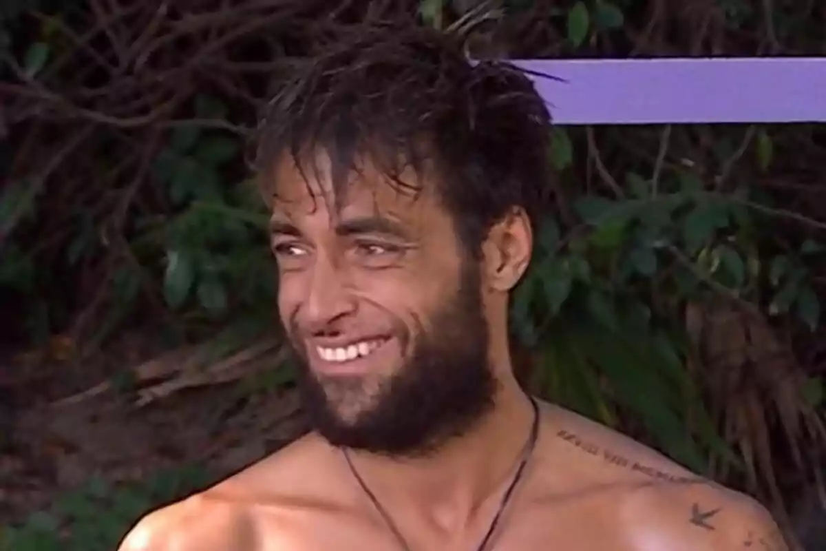 Montoya con barba y cabello despeinado sonríe al aire libre con vegetación de fondo en Supervivientes. Montoya con barba y cabello despeinado sonríe al aire libre con vegetación de fondo en Supervivientes.