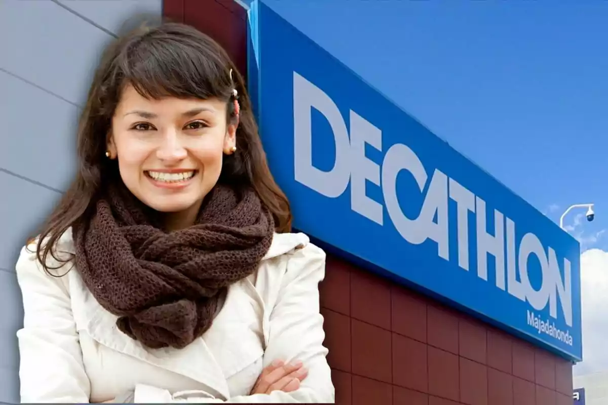 Una mujer sonriente con bufanda marrón y chaqueta clara frente a un cartel de Decathlon.