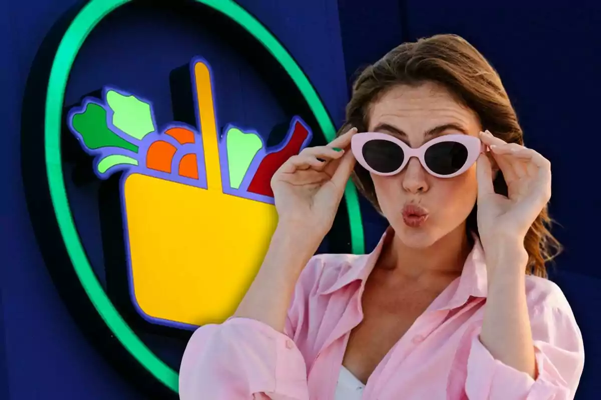 Una mujer con gafas de sol rosadas hace un gesto divertido frente a un cartel de supermercado colorido.