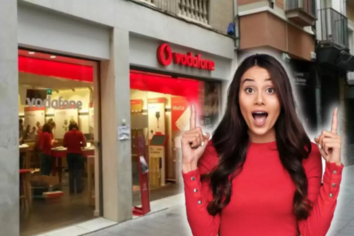 Una mujer con expresión de sorpresa y señalando hacia arriba frente a una tienda de Vodafone.
