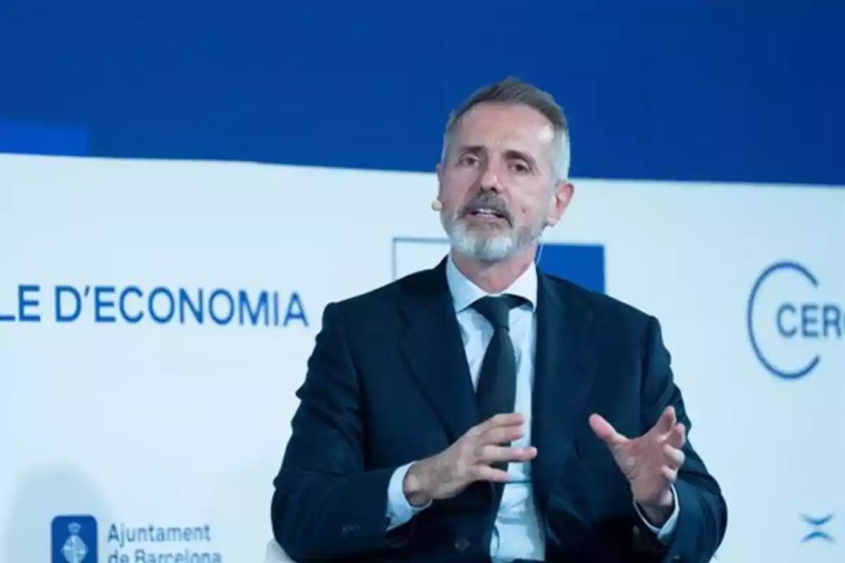 Un hombre con traje y corbata hablando en un evento de economía en Barcelona. Un hombre con traje y corbata hablando en un evento de economía en Barcelona.