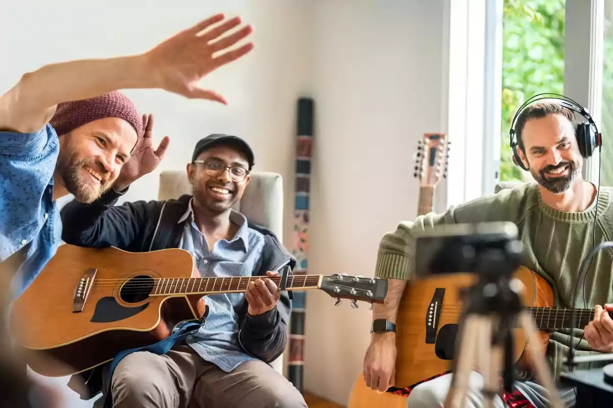 Tres hombres sonrientes tocando guitarras en una habitación iluminada por la luz natural.