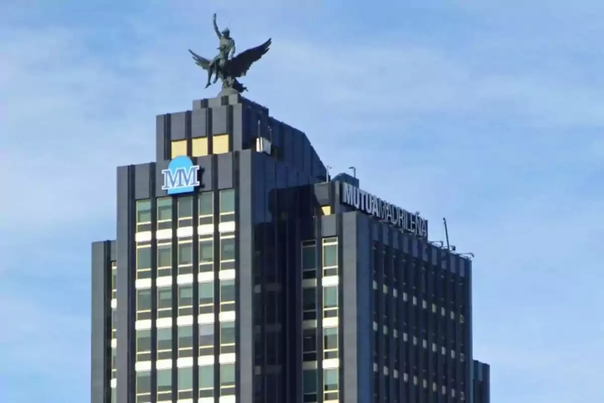 Edificio de la Mutua Madrileña con una estatua en la parte superior y el logo de MM.