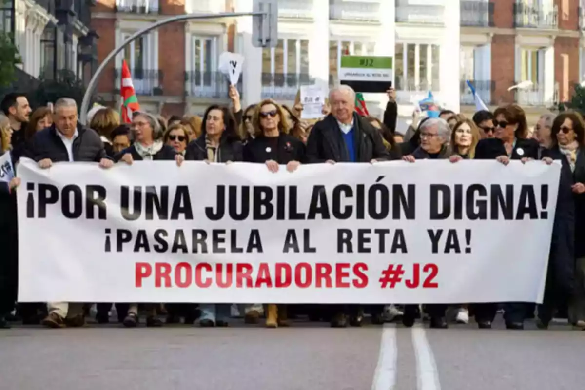 Personas sosteniendo una pancarta que dice "¡Por una jubilación digna! ¡Pasarela al RETA ya! Procuradores #J2" en una manifestación.