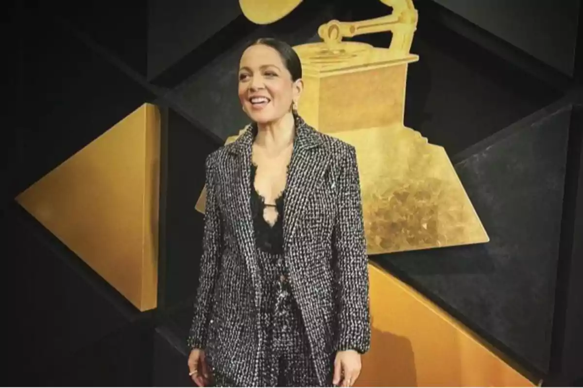 Una persona sonriente con un traje elegante frente a un fondo con un gramófono dorado.