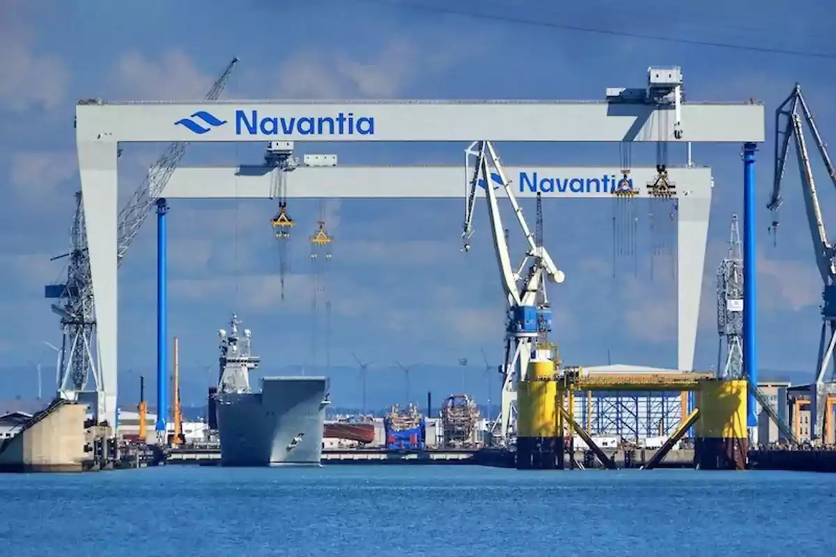 Astillero de Navantia con grúas y un barco en construcción en el puerto.