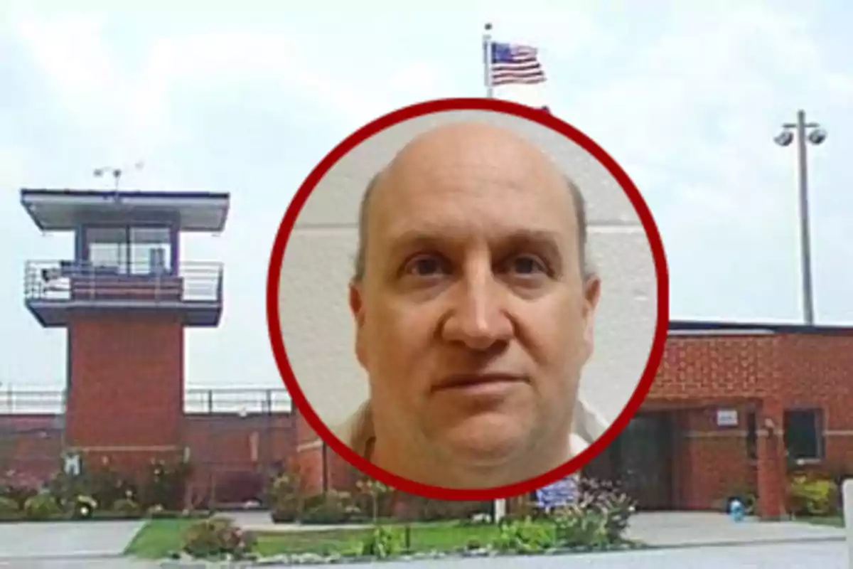 Hombre de rostro serio enmarcado en un círculo rojo sobre el fondo de una prisión con una torre de vigilancia y una bandera de Estados Unidos ondeando