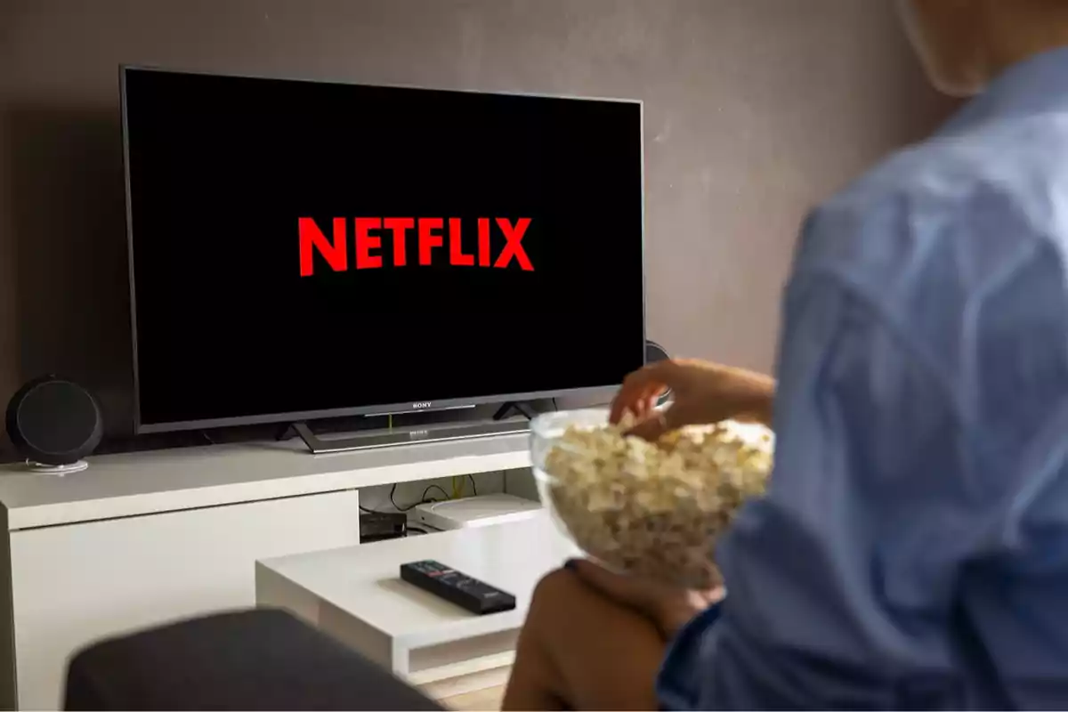 Persona viendo Netflix en la televisión mientras sostiene un tazón de palomitas.