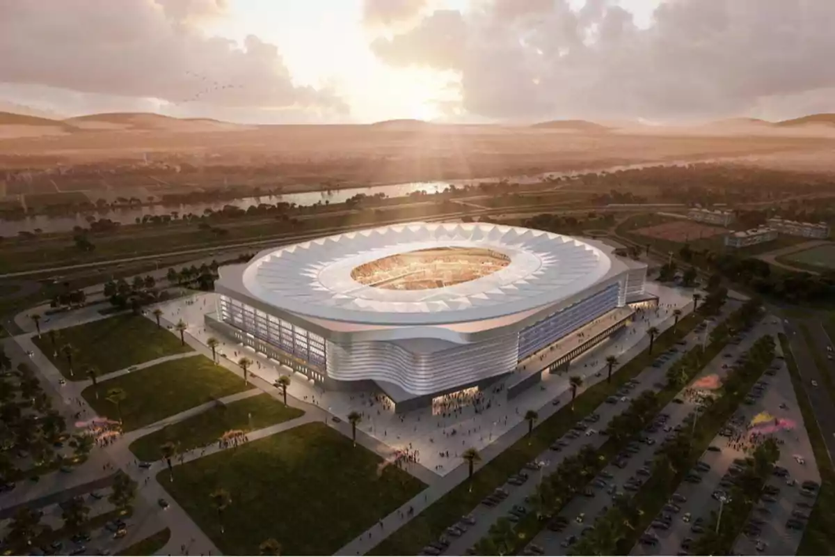 Vista aérea de un estadio moderno al atardecer con un diseño arquitectónico innovador y áreas verdes circundantes.