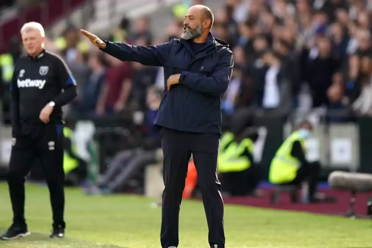 Un entrenador de fútbol en la línea lateral del campo dando instrucciones durante un partido. Un entrenador de fútbol en la línea lateral del campo dando instrucciones durante un partido.