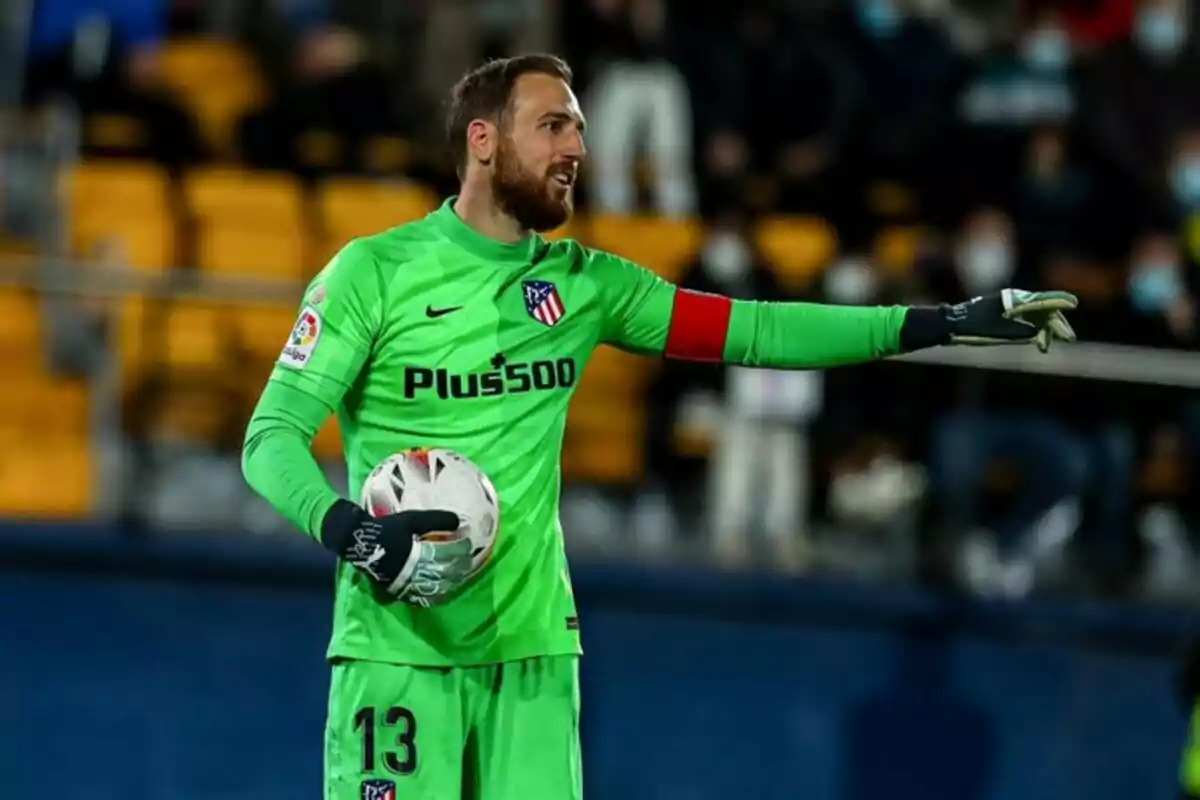 Un jugador de fútbol con uniforme verde sostiene un balón y señala con el brazo en un estadio. Un jugador de fútbol con uniforme verde sostiene un balón y señala con el brazo en un estadio.