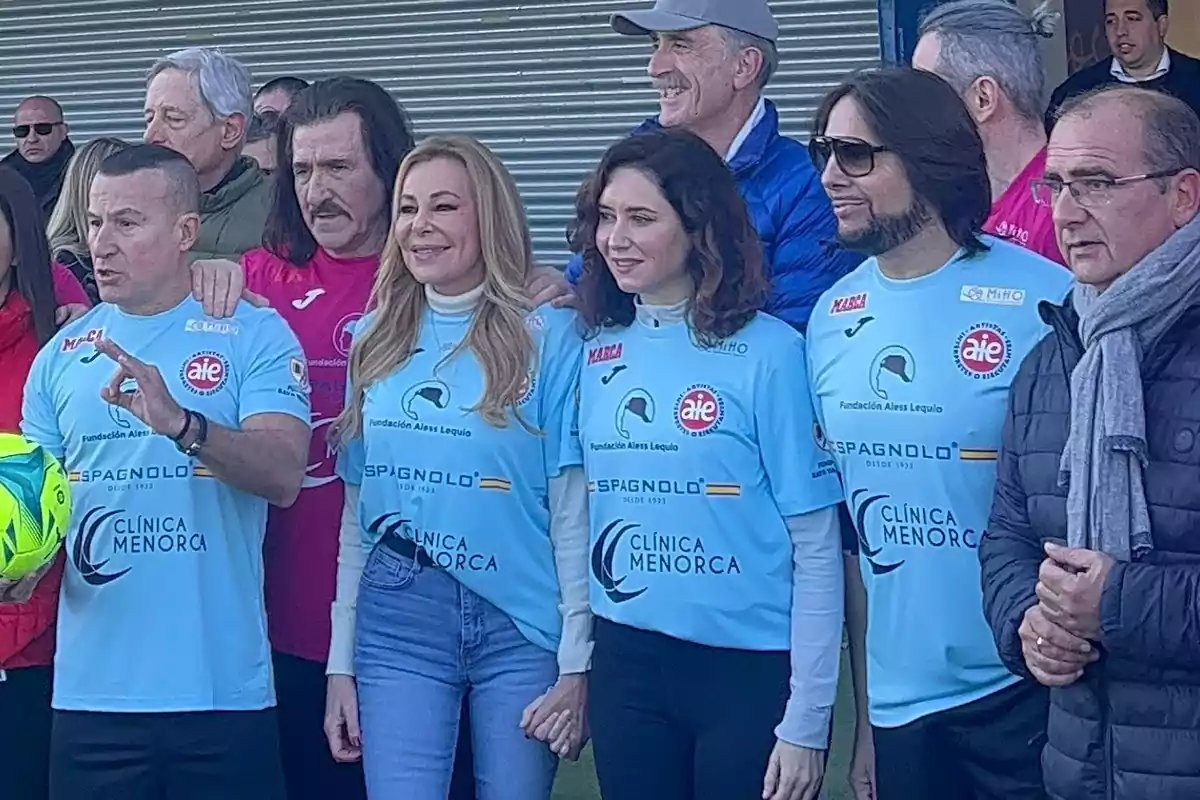 Un grupo de personas vestidas con camisetas deportivas azules posan juntas para una foto en un evento al aire libre.