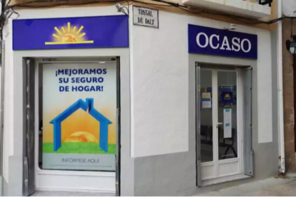 Fachada de una oficina de seguros Ocaso con un cartel promocional en la ventana que anuncia mejoras en el seguro de hogar Fachada de una oficina de seguros Ocaso con un cartel promocional en la ventana que anuncia mejoras en el seguro de hogar