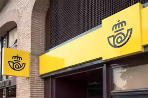 Fachada de una oficina de correos con letreros amarillos y el logotipo de la empresa.