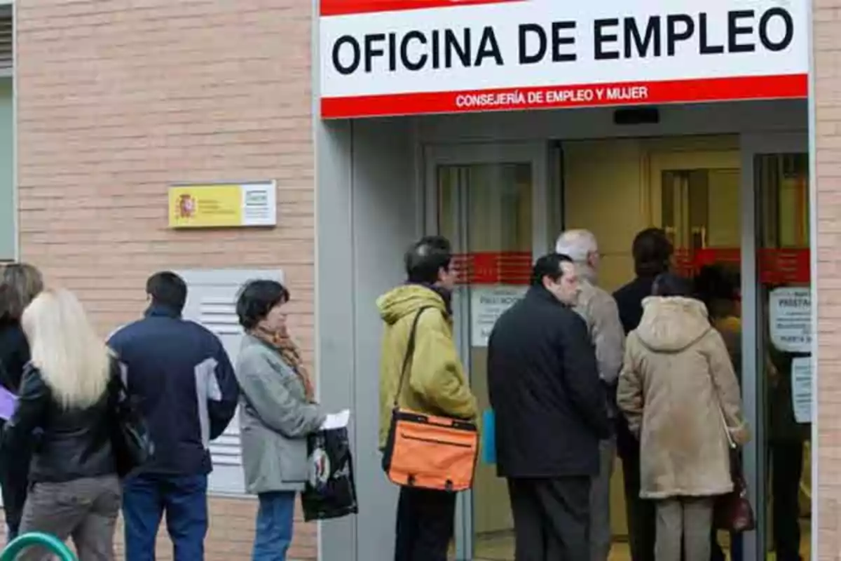 Personas haciendo fila en la entrada de una oficina de empleo.