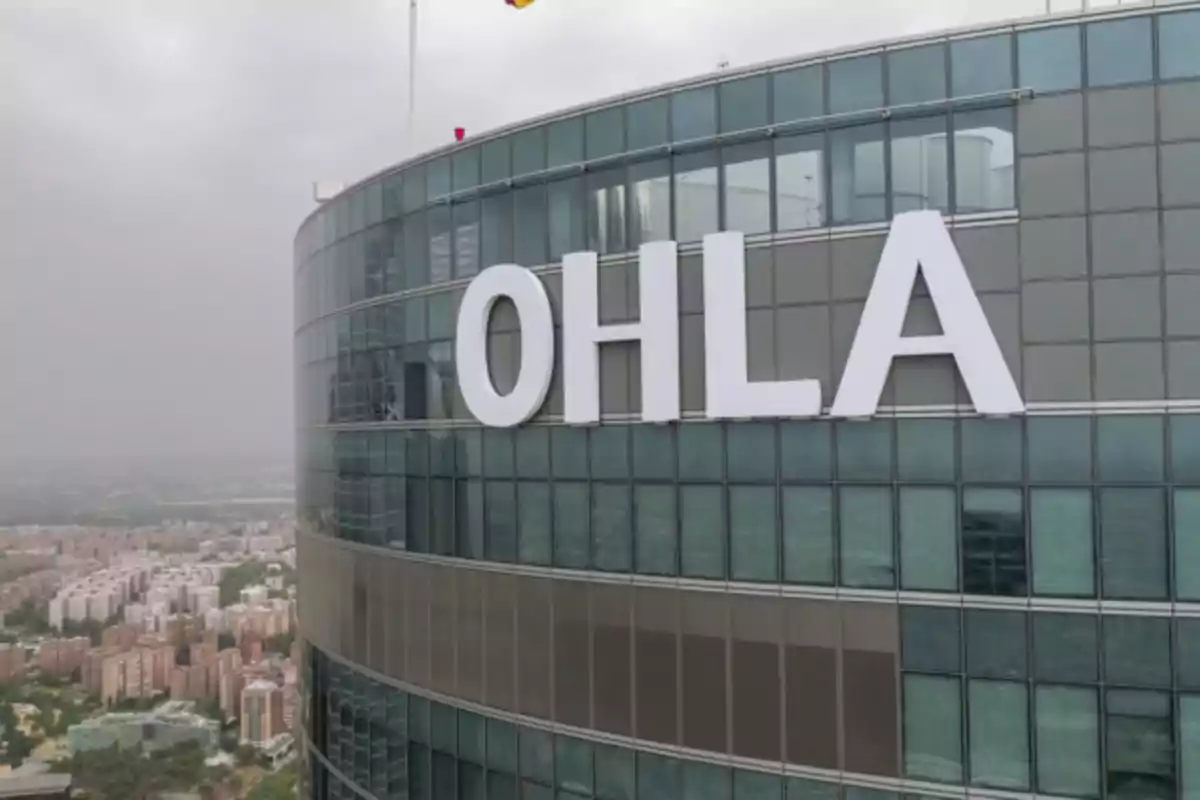 Edificio alto con fachada de vidrio y el logotipo "OHLA" en letras grandes blancas.