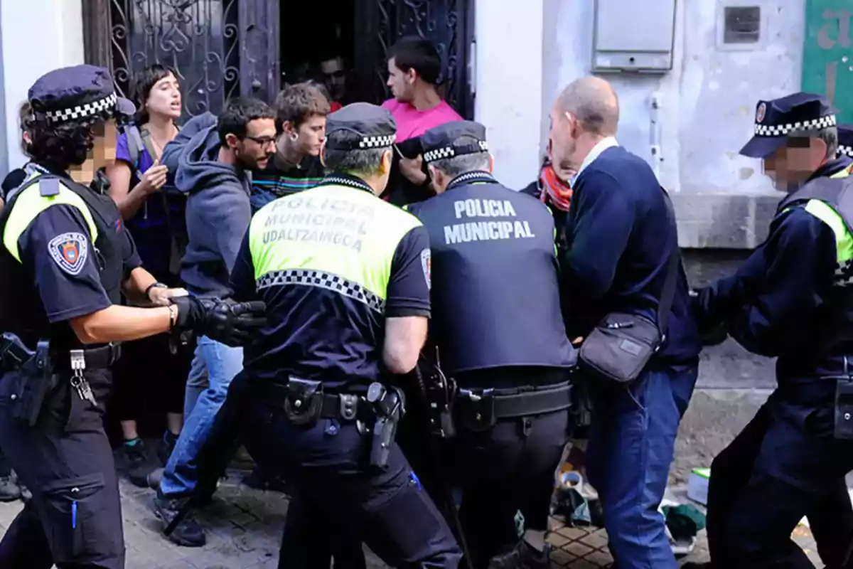 Un grupo de policías municipales interactúa con varias personas frente a un edificio.