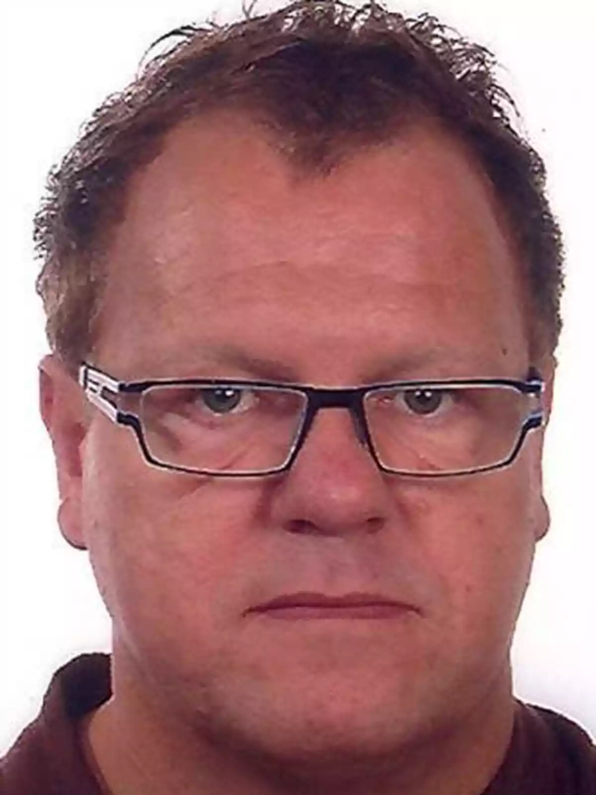 Un hombre con gafas y cabello corto mirando a la cámara.