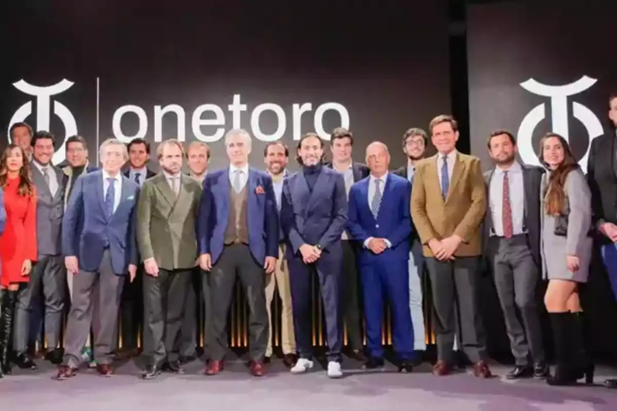 Un grupo de personas posando frente a un fondo con el logotipo y el nombre 