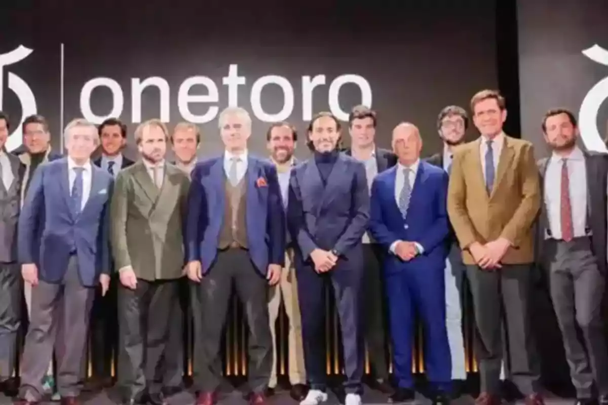 Un grupo de personas posando frente a un cartel que dice "onetoro".