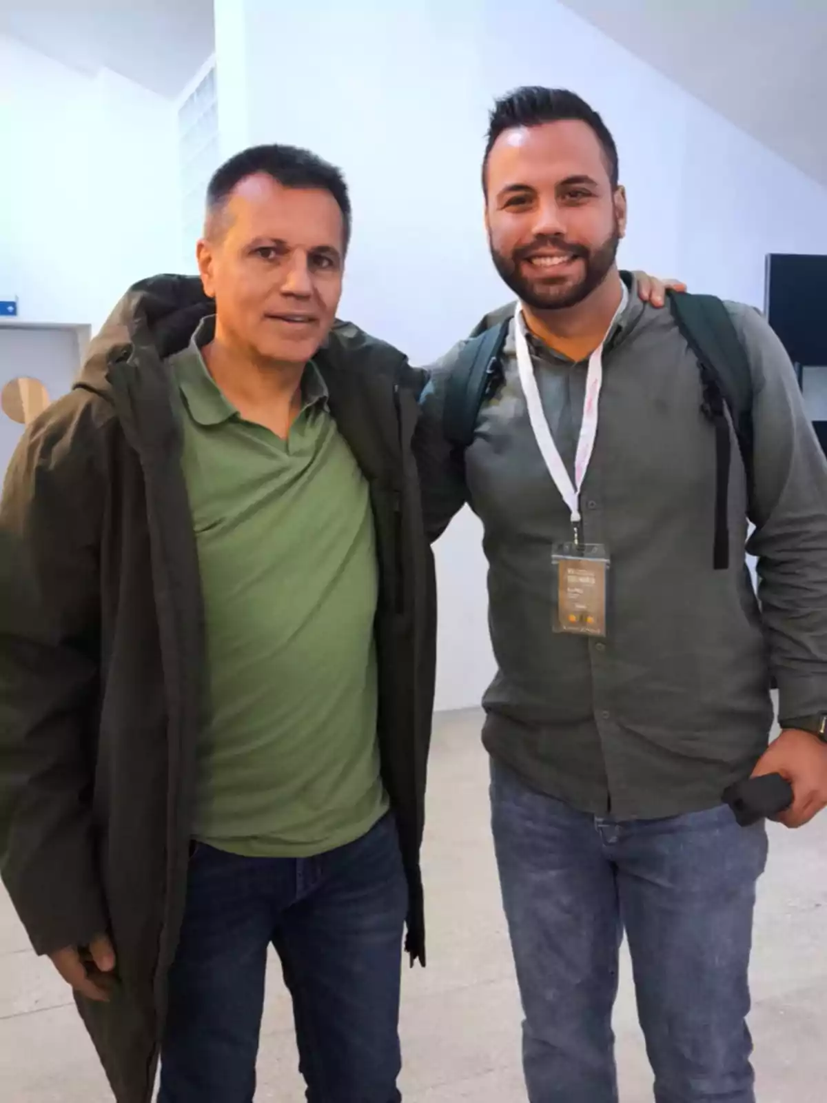 Dos personas posando juntas en un interior, ambas visten ropa casual y sonríen a la cámara.