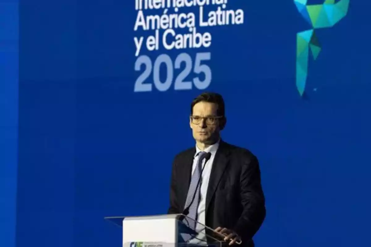 Un hombre de traje y corbata habla en un podio frente a un fondo azul que dice "Internacional América Latina y el Caribe 2025".