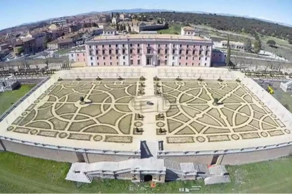 Vista aérea de un jardín formal con un edificio histórico al fondo.