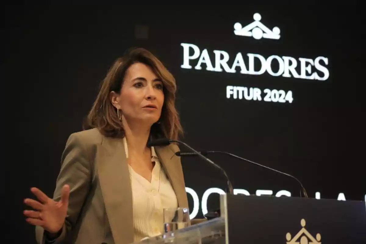 Mujer hablando en un podio durante un evento de Paradores en FITUR 2024.