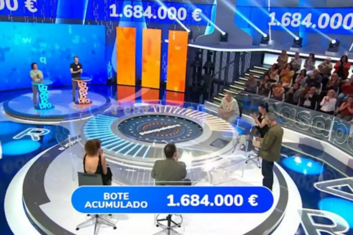 Concurso televisivo con participantes en un plató moderno, público al fondo y un bote acumulado de 1.684.000 euros en pantalla. Captura de 'Pasapalabra' Concurso televisivo con participantes en un plató moderno, público al fondo y un bote acumulado de 1.684.000 euros en pantalla. Captura de 'Pasapalabra'