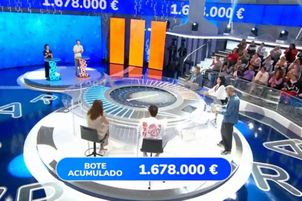 Un plató de concurso televisivo con concursantes, presentador, público y un bote acumulado de un millón seiscientos setenta y ocho mil euros en pantalla. Captura de 'Pasapalabra' Un plató de concurso televisivo con concursantes, presentador, público y un bote acumulado de un millón seiscientos setenta y ocho mil euros en pantalla. Captura de 'Pasapalabra'