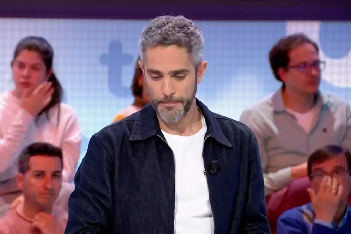 Roberto Leal, vestido con chaqueta oscura y camiseta blanca, está en un estudio de televisión con personas sentadas al fondo. Captura de 'Pasapalabra' Roberto Leal, vestido con chaqueta oscura y camiseta blanca, está en un estudio de televisión con personas sentadas al fondo. Captura de 'Pasapalabra'