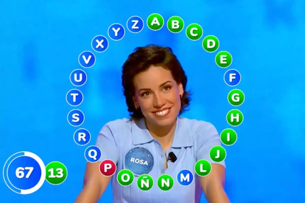 Rosa sonriente participando en un concurso de televisión con letras del abecedario rodeándola y un marcador de tiempo y aciertos a la izquierda. Captura de 'Pasapalabra' Rosa sonriente participando en un concurso de televisión con letras del abecedario rodeándola y un marcador de tiempo y aciertos a la izquierda. Captura de 'Pasapalabra'