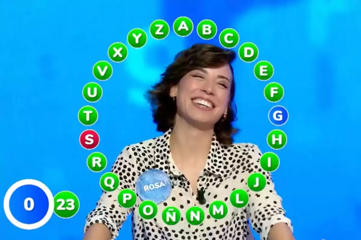 Rosa sonriente participa en un concurso de televisión con letras del abecedario rodeándola en la pantalla. Captura de 'Pasapalabra' Rosa sonriente participa en un concurso de televisión con letras del abecedario rodeándola en la pantalla. Captura de 'Pasapalabra'