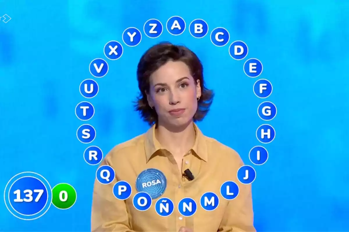 Rosa concursando en un programa de televisión con letras del abecedario en círculo a su alrededor y un marcador con el número 137. Captura de 'Pasapalabra' Rosa concursando en un programa de televisión con letras del abecedario en círculo a su alrededor y un marcador con el número 137. Captura de 'Pasapalabra'