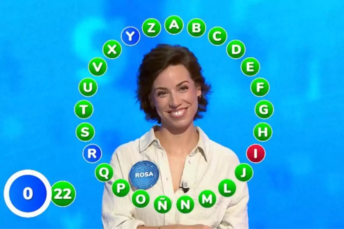 Rosa sonriente participando en un concurso de televisión con letras del abecedario en círculo y un marcador de tiempo y aciertos. Captura de 'Pasapalabra' Rosa sonriente participando en un concurso de televisión con letras del abecedario en círculo y un marcador de tiempo y aciertos. Captura de 'Pasapalabra'