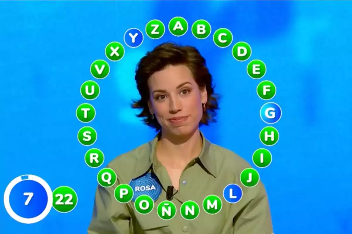 Rosa participando en un concurso de televisión con letras del abecedario en un círculo a su alrededor y un cronómetro en la esquina inferior izquierda. Captura de 'Pasapalabra' Rosa participando en un concurso de televisión con letras del abecedario en un círculo a su alrededor y un cronómetro en la esquina inferior izquierda. Captura de 'Pasapalabra'