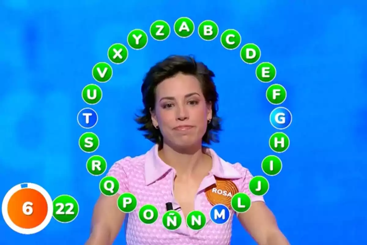 Rosa participando en un concurso de televisión con un círculo de letras alrededor y un cronómetro en la esquina inferior izquierda. Captura de 'Pasapalabra' Rosa participando en un concurso de televisión con un círculo de letras alrededor y un cronómetro en la esquina inferior izquierda. Captura de 'Pasapalabra'