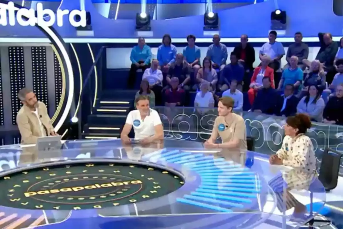 Un grupo de personas participa en un programa de televisión, sentados alrededor de una mesa circular con un público al fondo. Captura de 'Pasapalabra' Un grupo de personas participa en un programa de televisión, sentados alrededor de una mesa circular con un público al fondo. Captura de 'Pasapalabra'