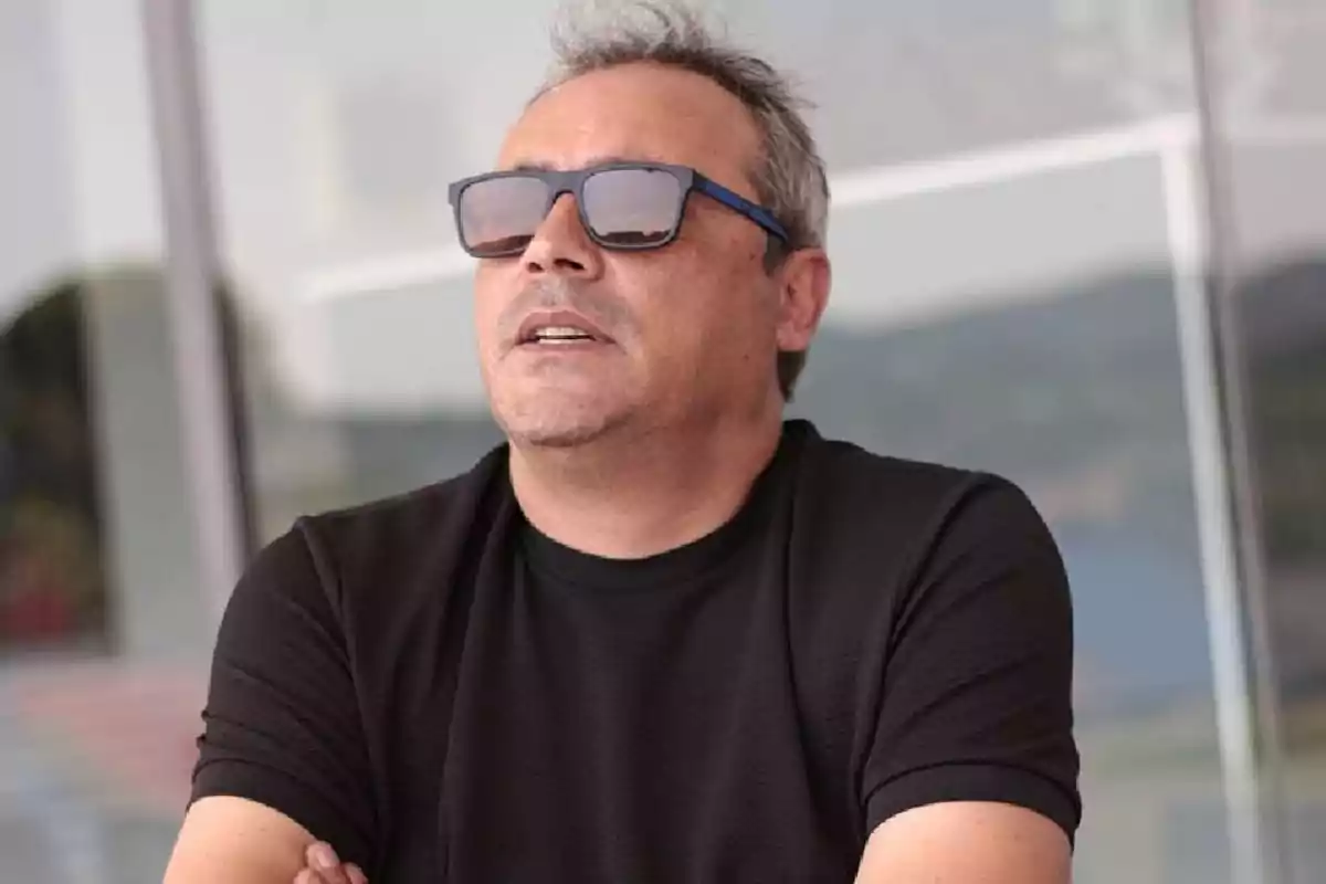 Un hombre con gafas de sol y camiseta negra mirando hacia arriba. Un hombre con gafas de sol y camiseta negra mirando hacia arriba.