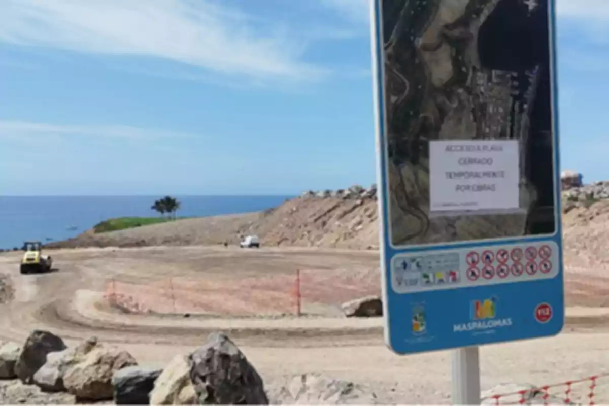 Cartel informativo en primer plano que indica el cierre temporal de una playa por obras con maquinaria y un coche al fondo en una zona costera en construcción Cartel informativo en primer plano que indica el cierre temporal de una playa por obras con maquinaria y un coche al fondo en una zona costera en construcción