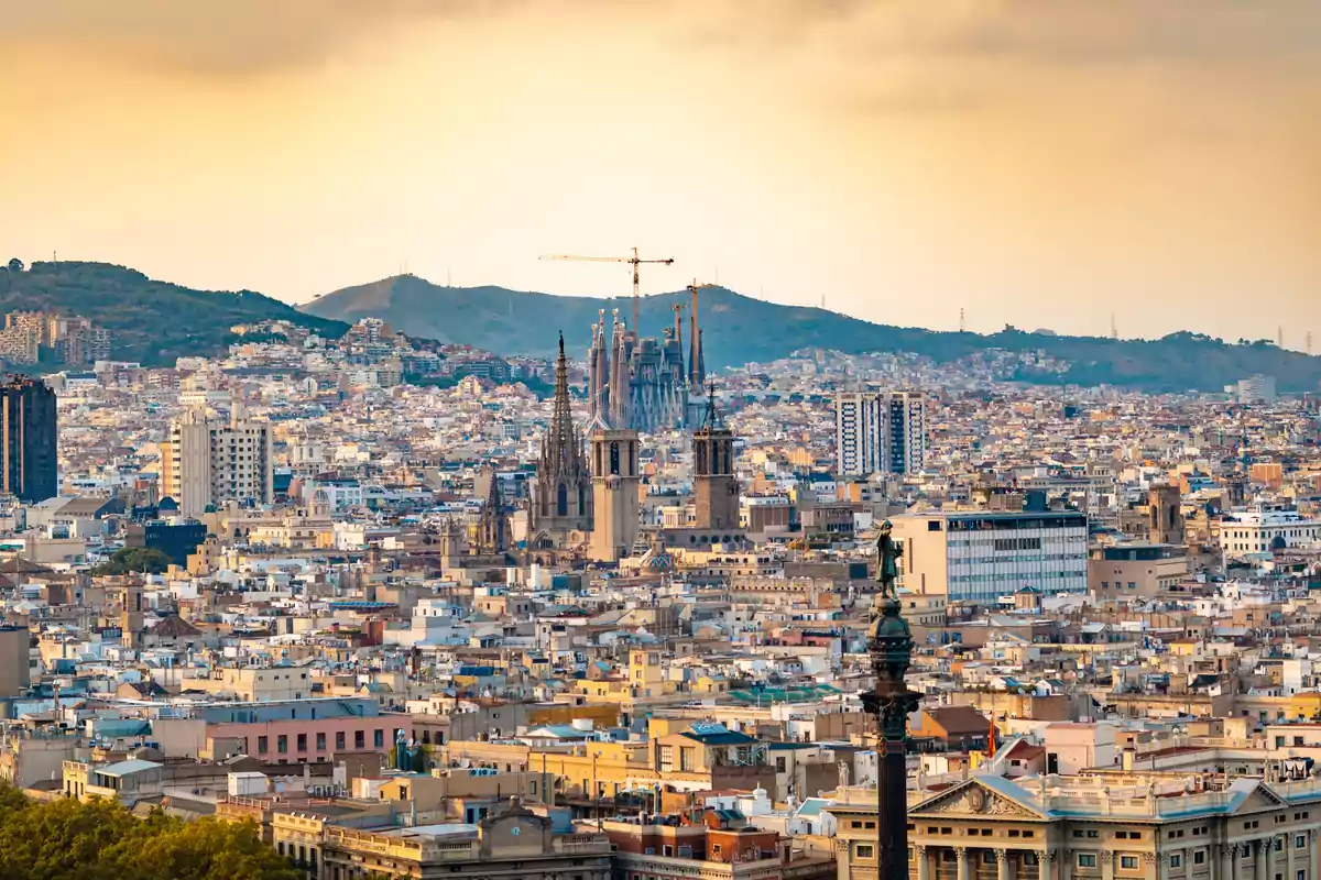 Vista panorámica de la ciudad de Barcelona con la Sagrada Familia y otros edificios emblemáticos al atardecer.